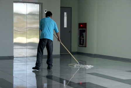Man moping the tiled floor in a commercial building
